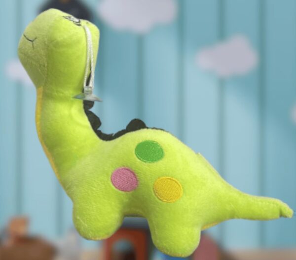 Peluche de dinosaurio de cuello largo color verde, con chupón para colgar en algún apartado de vidrio o espejo, con un fondo azul